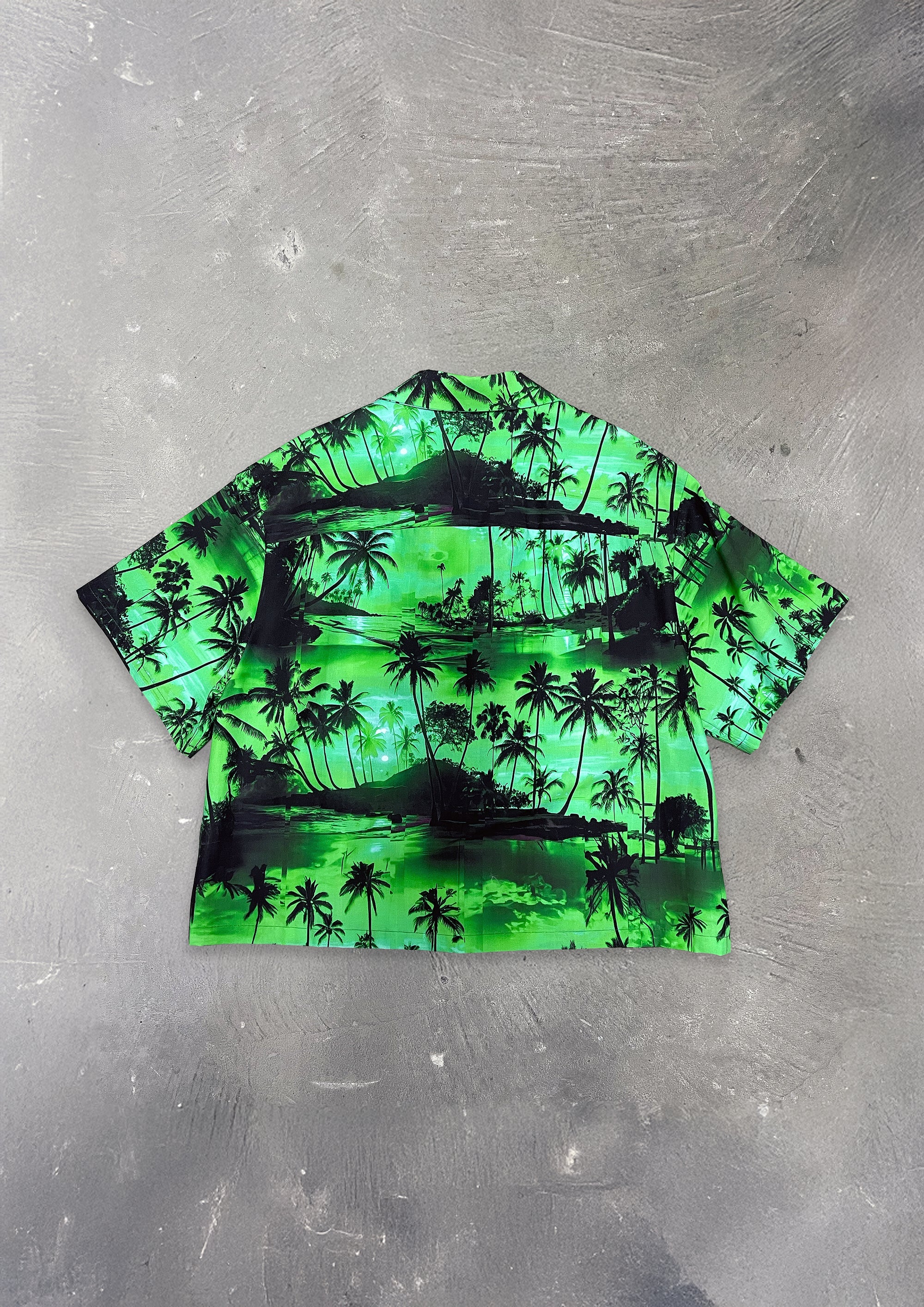 Green and black tropical print shirt on a gray surface