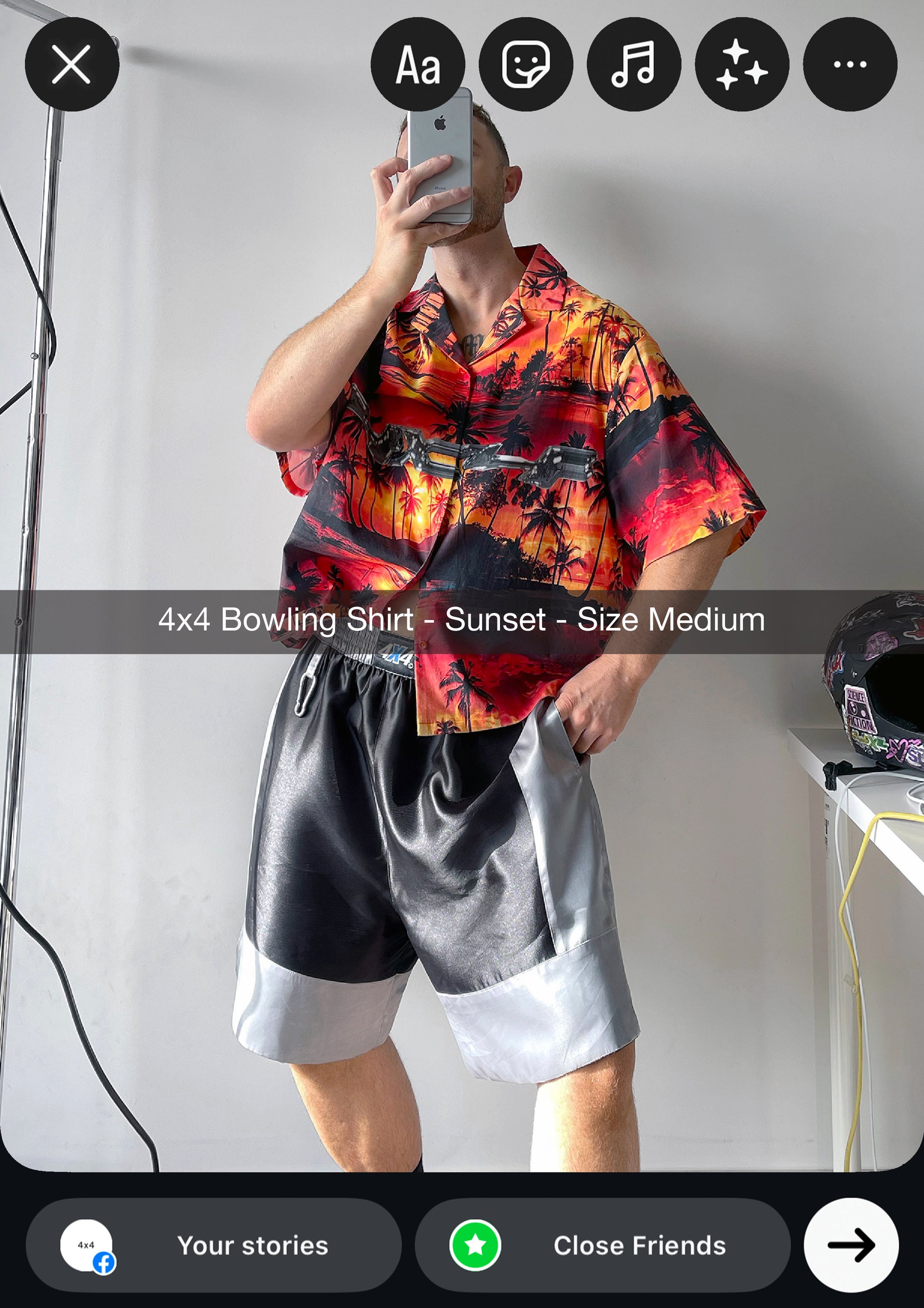Person wearing a colorful 4x4 bowling shirt and gray shorts, taking a mirror selfie.