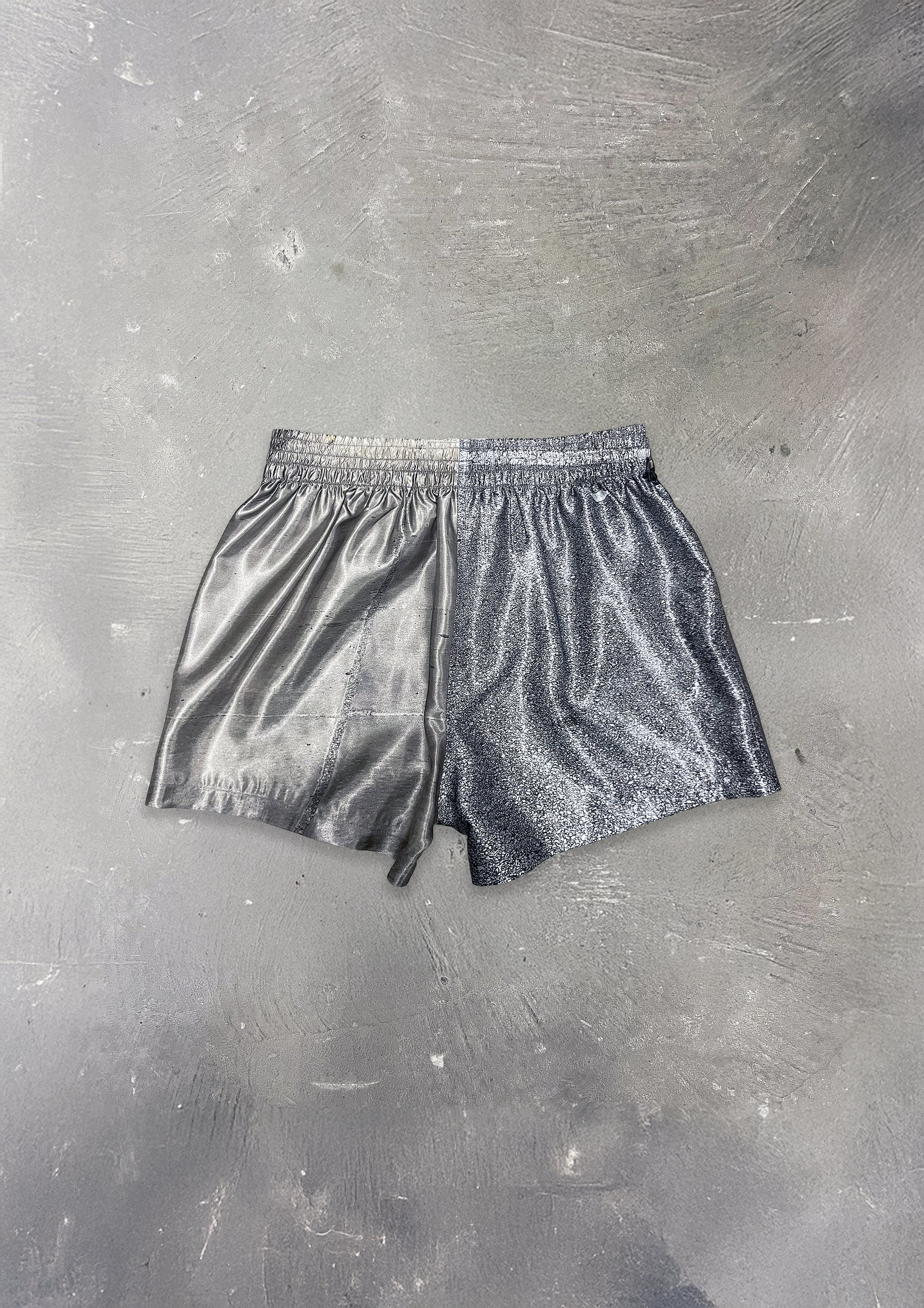 Silver metallic shorts on a textured gray background