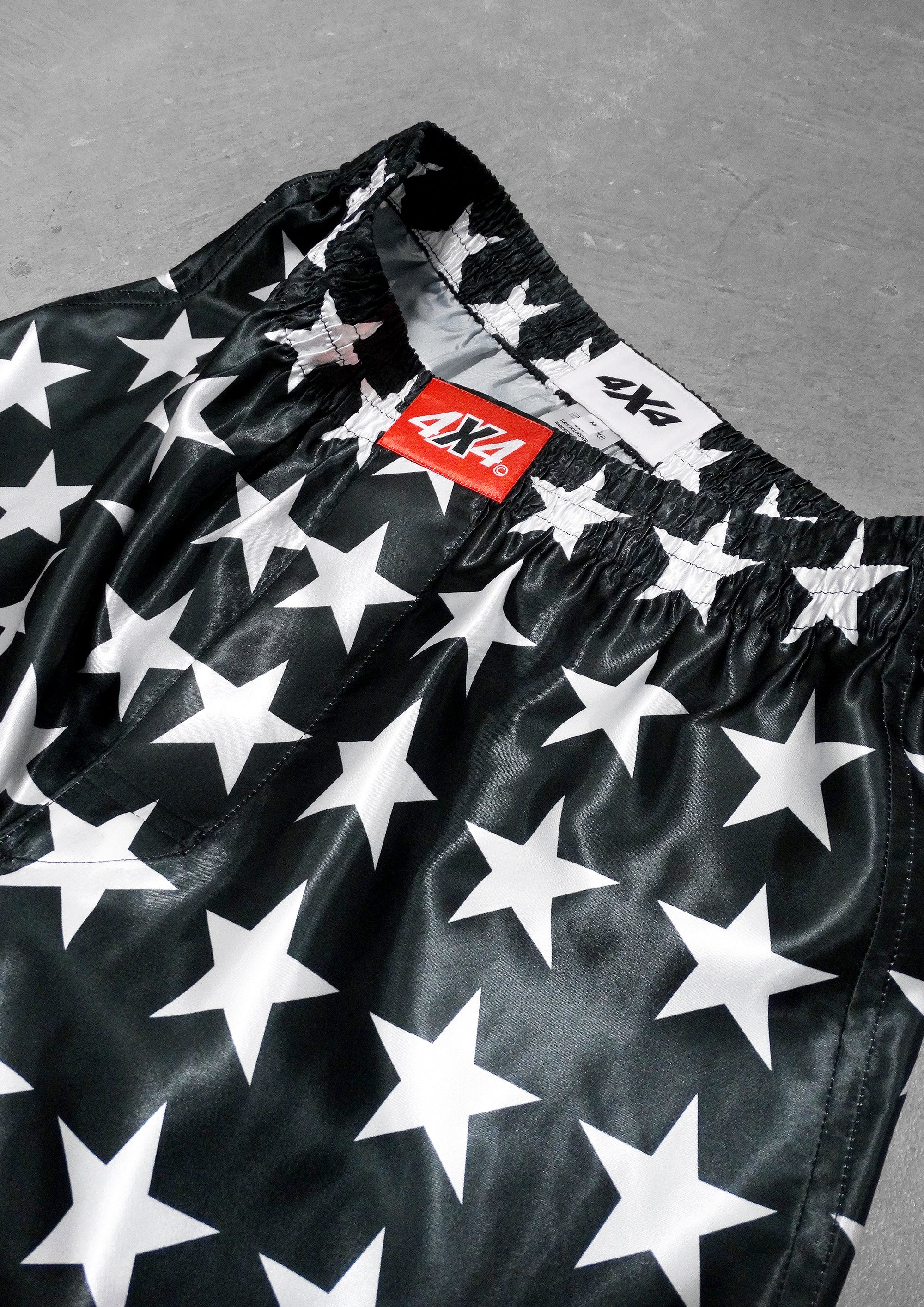 Black shorts with white star pattern and a red '4X4' label on a gray background