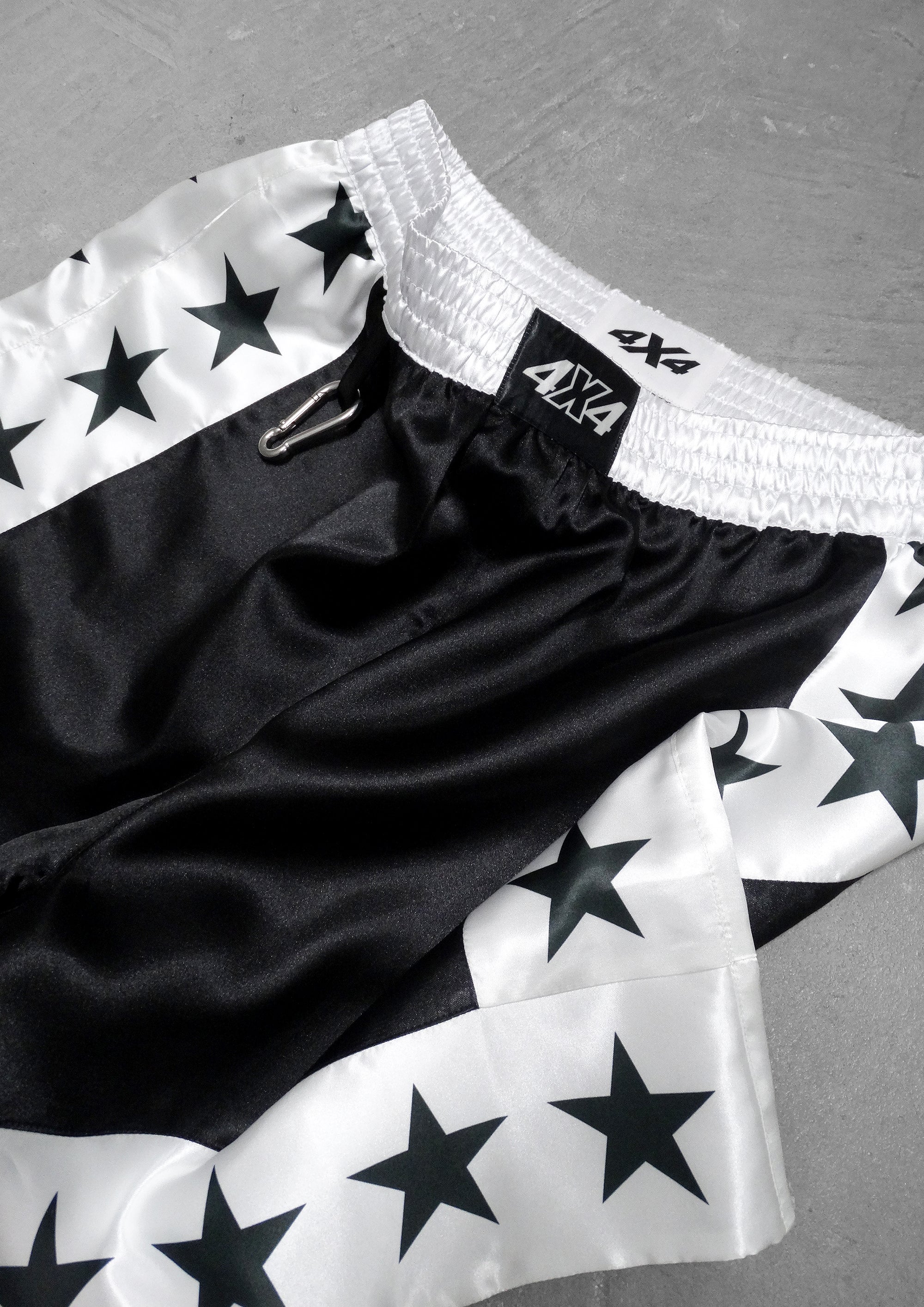 Black and white shorts with star pattern and '4X4' branding on a gray surface