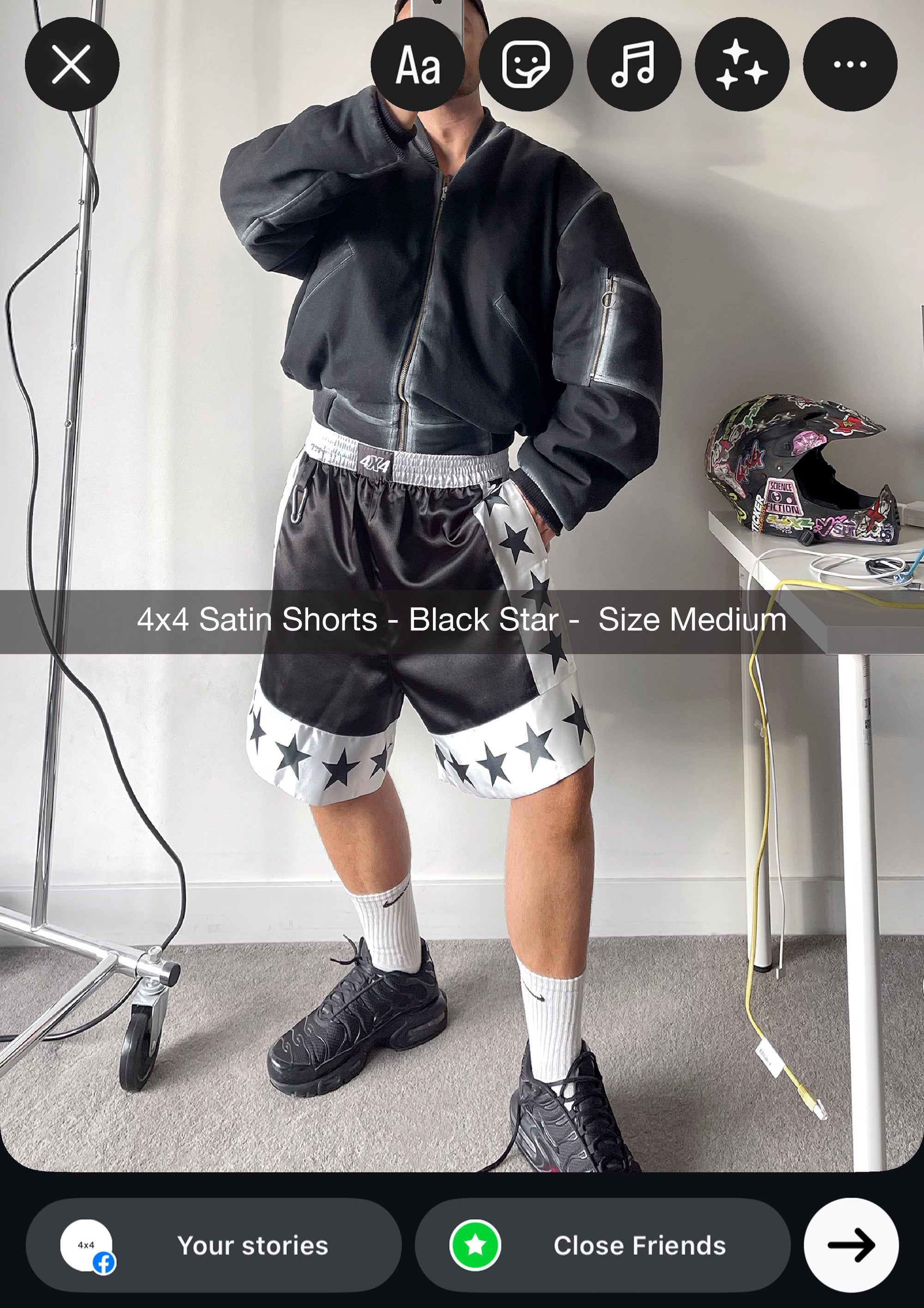 Person wearing black satin shorts with star patterns in a minimal indoor setting.