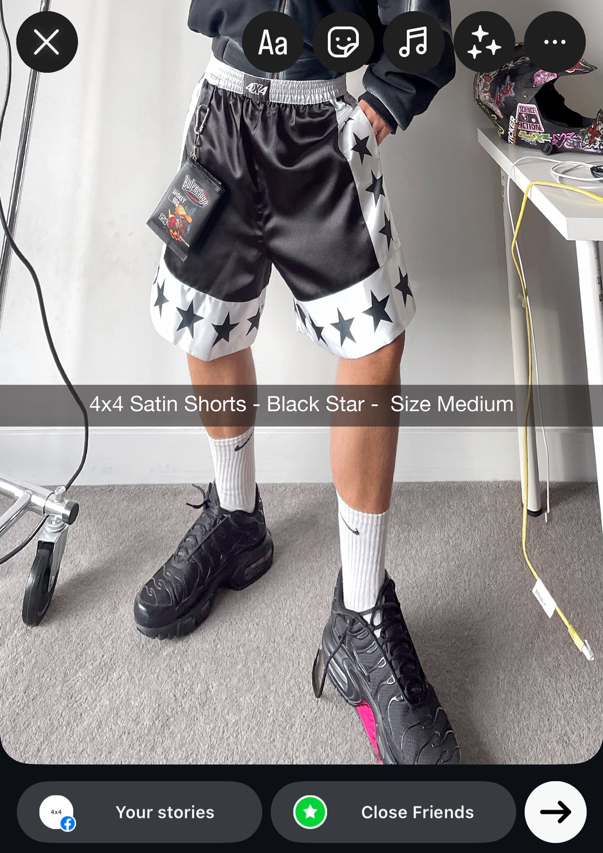 Person wearing black satin shorts with star patterns in a room.