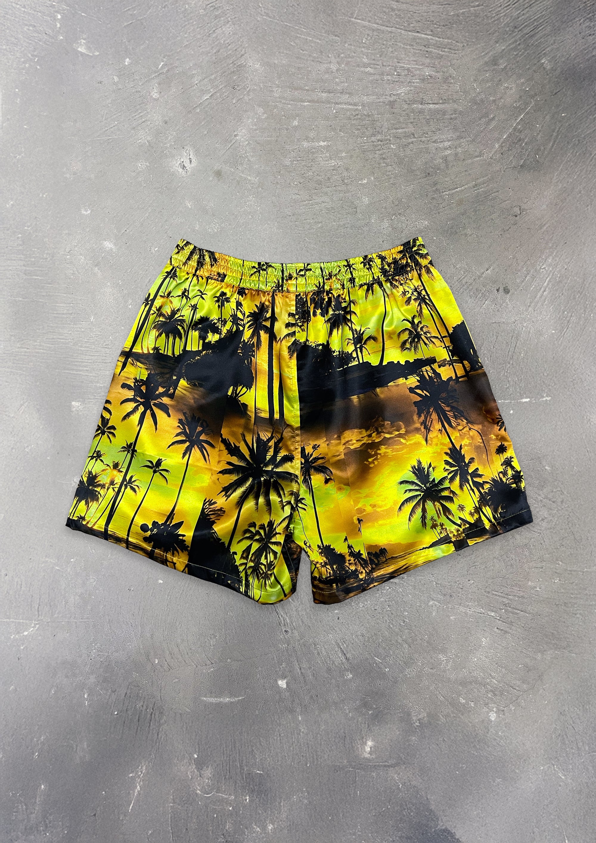 Yellow and black palm tree patterned shorts on a gray surface