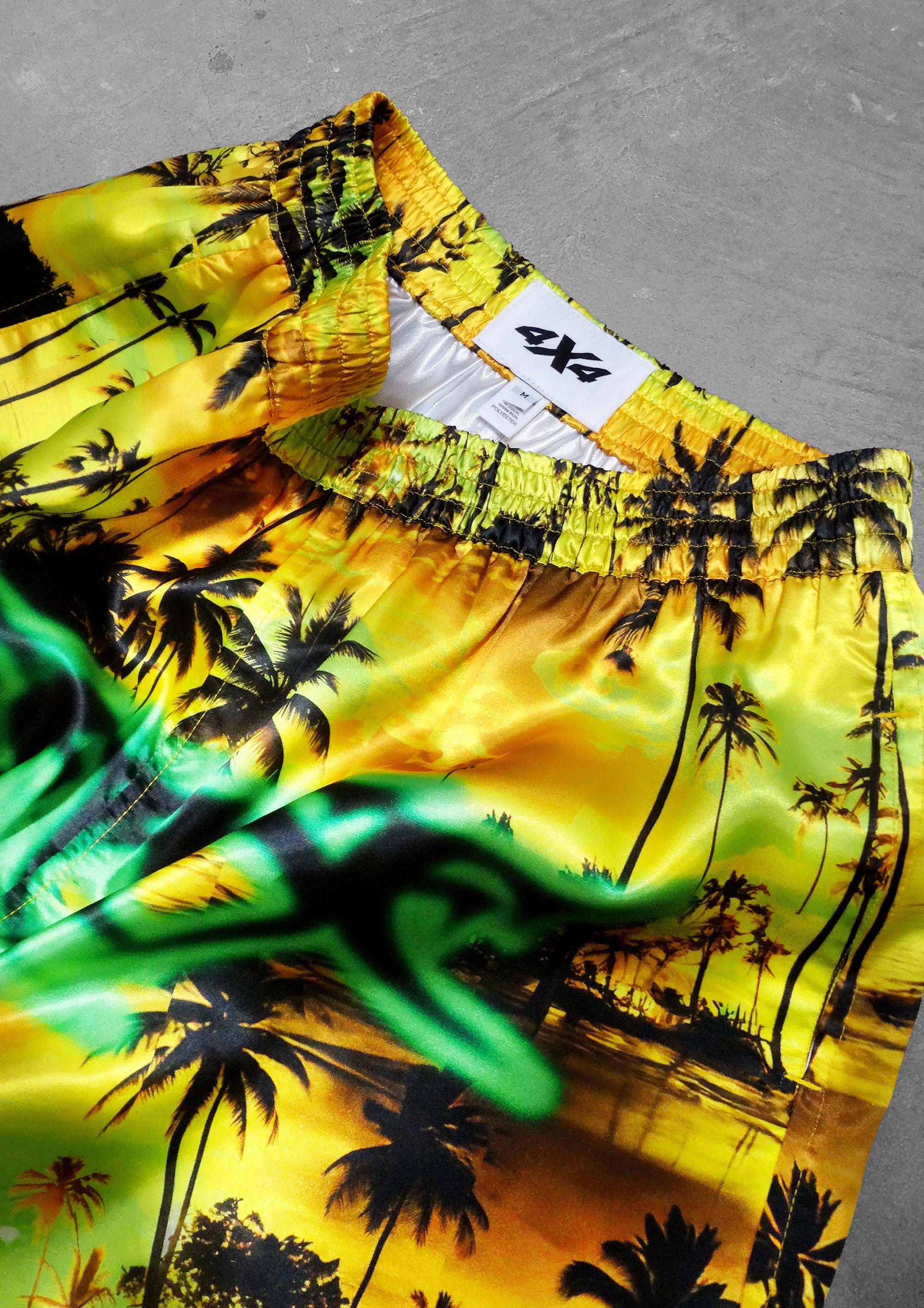 Colorful beach shorts with palm tree design on a gray surface