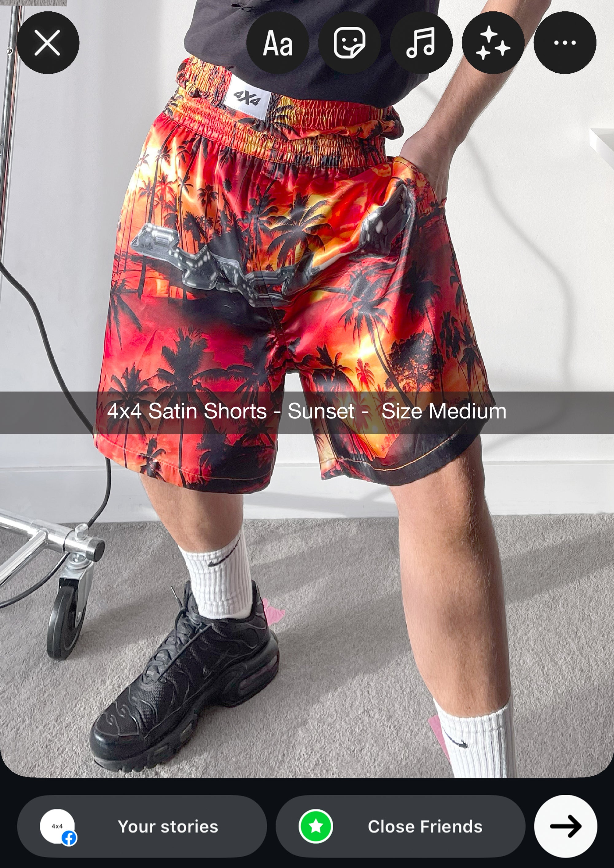 Person wearing colorful satin shorts with a palm tree pattern on a plain background