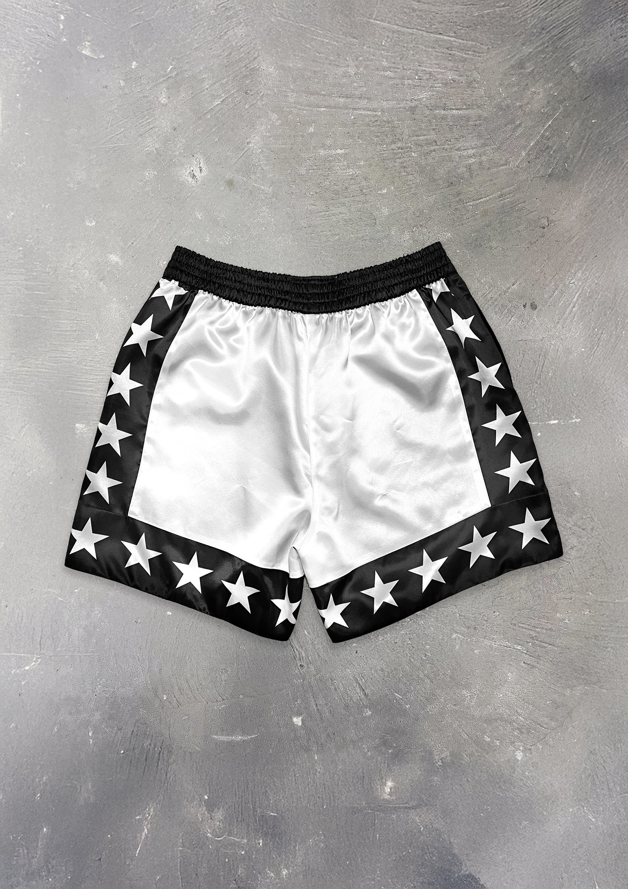 White shorts with black trim and star patterns on a metallic surface