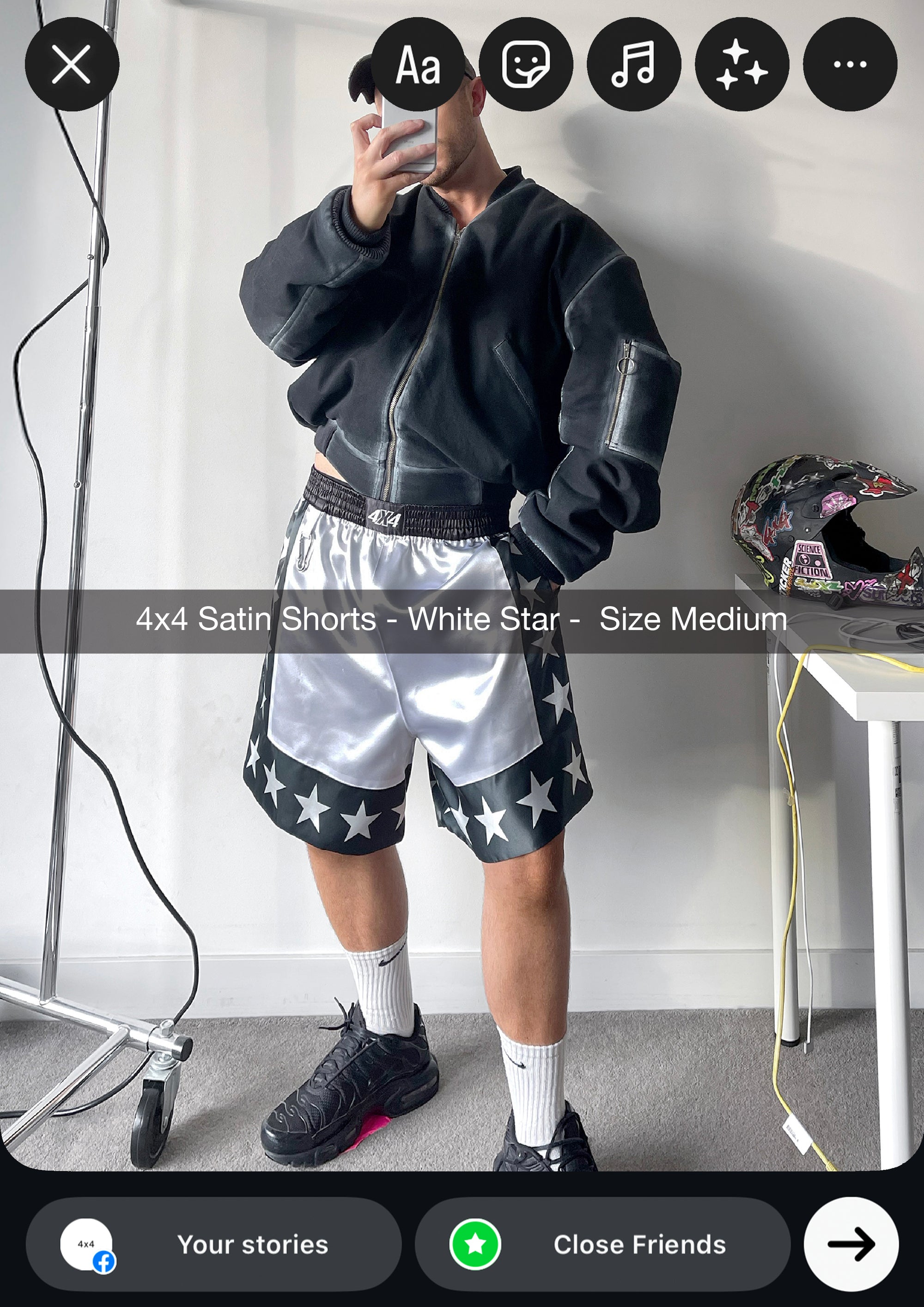 Person wearing satin shorts with star patterns in a minimal indoor setting.