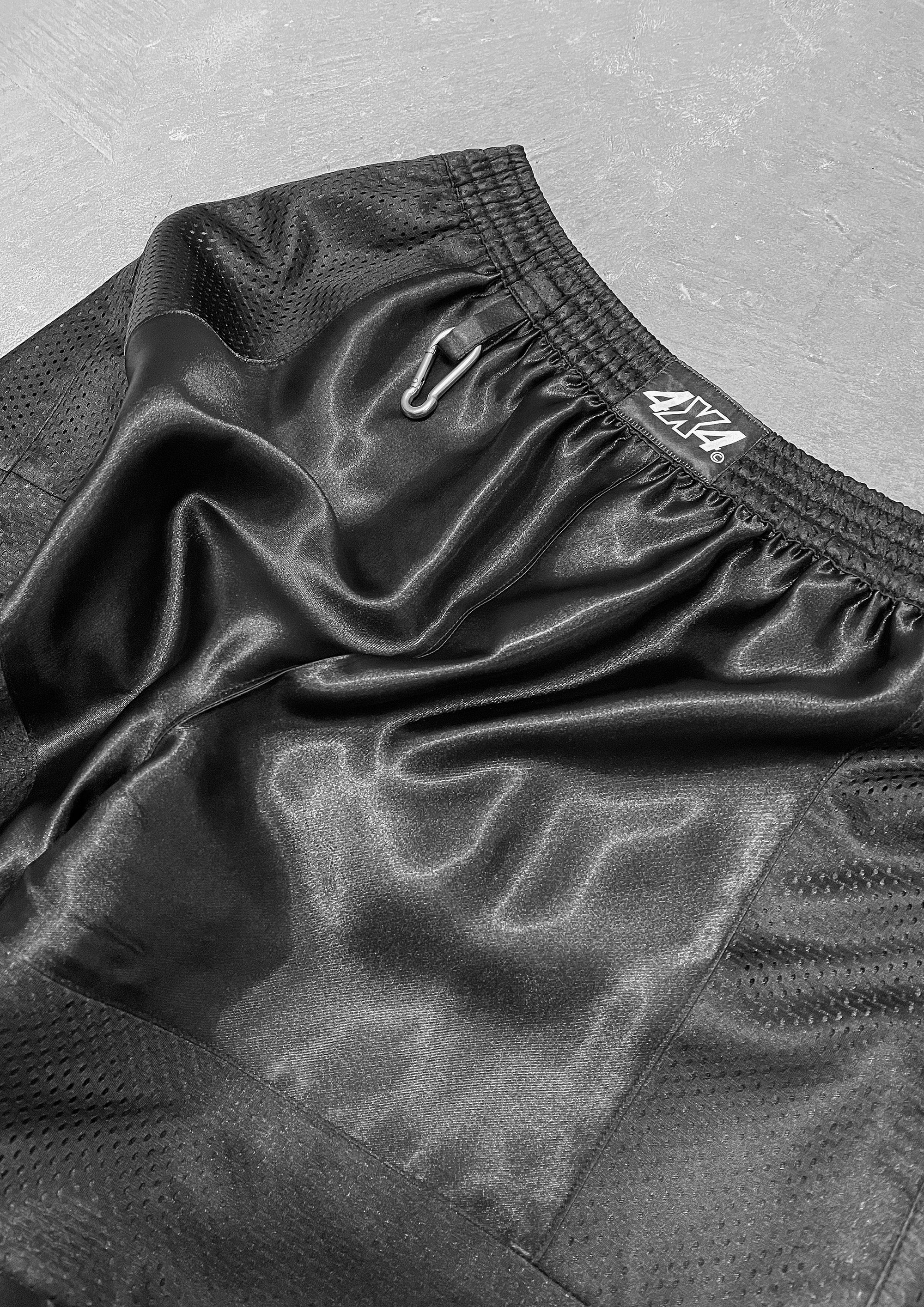 Black athletic shorts with a brand logo on a gray background