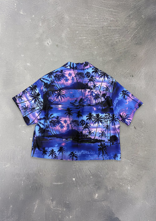 Short-sleeve shirt with palm tree and sunset design on a textured gray background