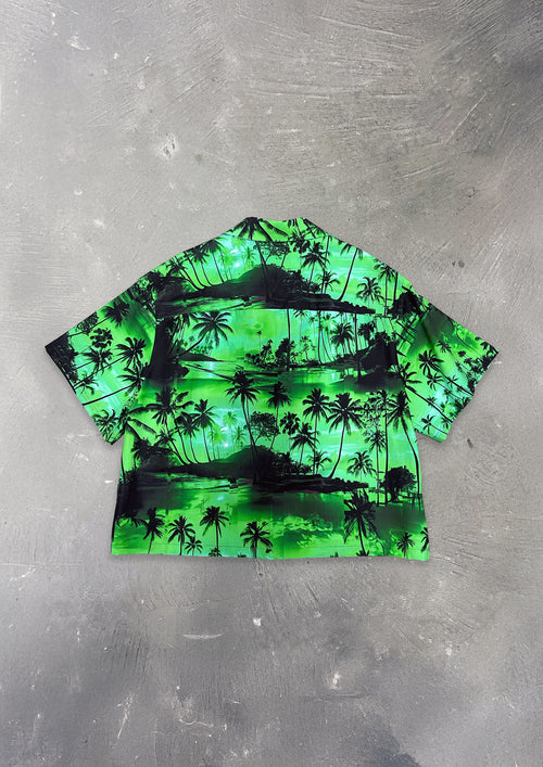 Green and black tropical print shirt on a gray surface